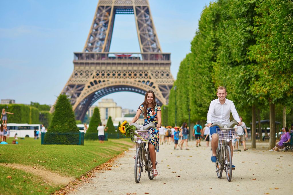 Pareja yendo en bici frente a la torre Eiffel